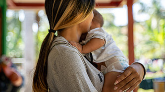 Jugendliche hält ihr Baby im Arm.