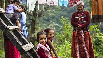 Kinder aus Nepal sitzen auf einer Bank