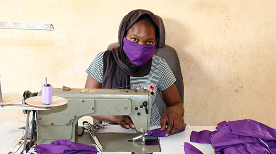 Une fille en train de coudre des masques