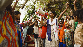Mädchen und jungen Frauen erheben an einer Versammlung die Faust .