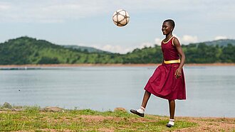 Mädchen aus Ghana spielt mit einem Ball.