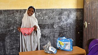In Nigeria zeigt ein Mädchen vor, wie von Plan zur Verfügung gestellte, wiederverwendbare Menstruationsprodukte angewendet werden.