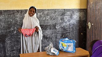 In Nigeria zeigt ein Mädchen vor, wie von Plan zur Verfügung gestellte, wiederverwendbare Menstruationsprodukte angewendet werden.