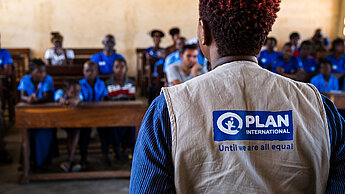 Mitarbeiterin von Plan International arbeitet mit Kindern und Jugendlichen in einem Projekt.