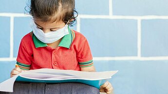 Un enfant avec un masque est en train de lire