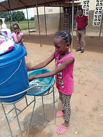 Ein Mädchen wäscht sich an einer von Plan eingerichteten Handwaschstation in Sambia die Hände